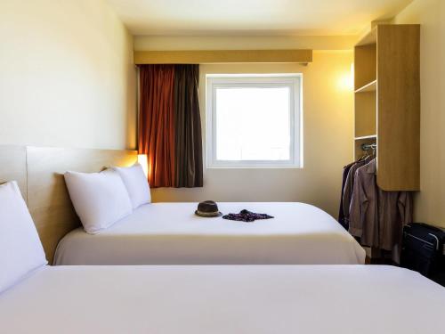 a hotel room with two beds and a window at Ibis Juarez Consulado in Ciudad Juárez