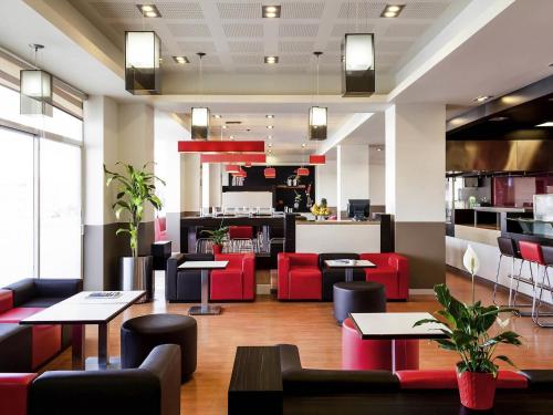 a restaurant with tables and red chairs and a counter at Ibis Juarez Consulado in Ciudad Juárez