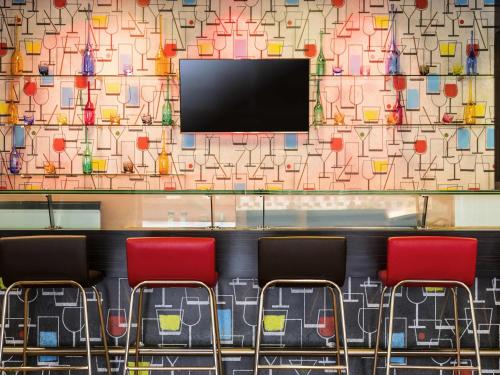 a wall with three red chairs and a tv at Ibis Juarez Consulado in Ciudad Juárez