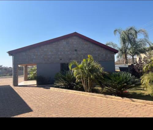 a brick building with a garage and palm trees at Elon moreh Lodges in Lusaka