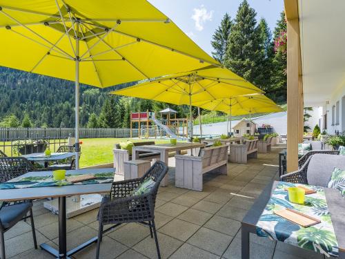 a patio with tables and chairs with yellow umbrellas at Natürlich Hotel mit Charakter in Fiss