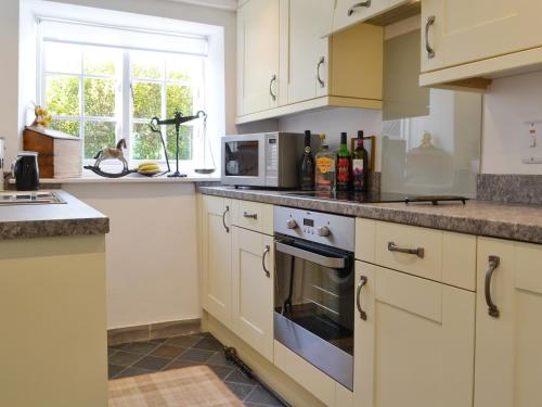 a kitchen with white cabinets and a microwave at Toad Hall in Helmsley