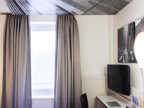 Una televisión o centro de entretenimiento en Ibis Styles Strasbourg Centre Gare
