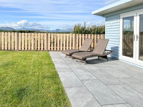 two chairs sitting on a patio next to a fence at Bod Eithin in Harlech