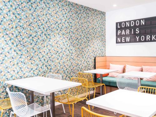a dining room with tables and chairs and a wall at ibis Styles Macon Centre in Mâcon