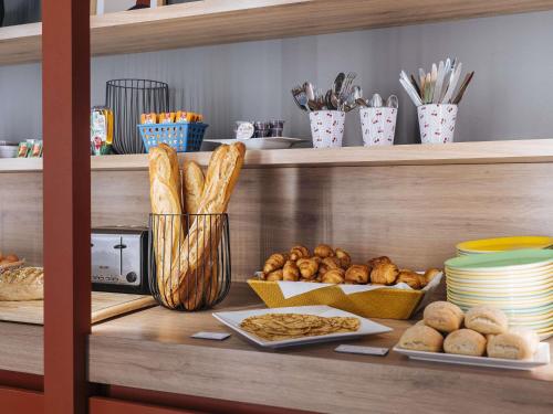 una estantería con varios tipos de pan y repostería en ibis Styles Le Mans Gare Sud, en Le Mans