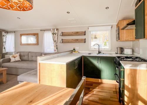 a kitchen with green cabinets and a couch at Fir Trees in Chester