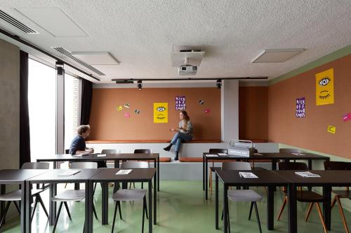 two women sitting in a room with tables and chairs at The Social Hub Eindhoven Extended Stay in Eindhoven
