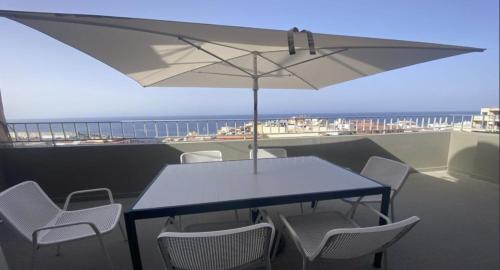 a table with chairs and an umbrella on a balcony at Atico ULISES in Valle Gran Rey