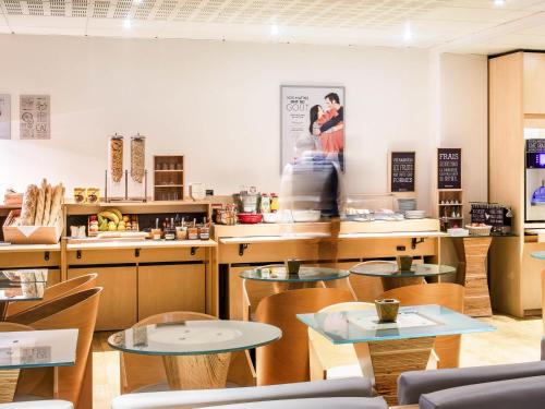 a restaurant with tables and chairs and a kitchen at ibis Quimperle in Quimperlé