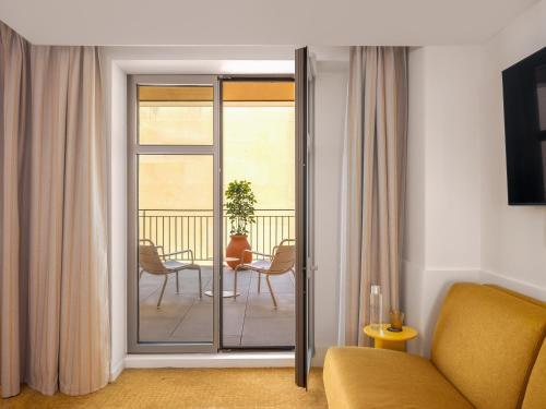a living room with a sliding glass door to a balcony at Hôtel Saint Christophe Aix en Provence Centre Ville by Germain Collection in Aix-en-Provence