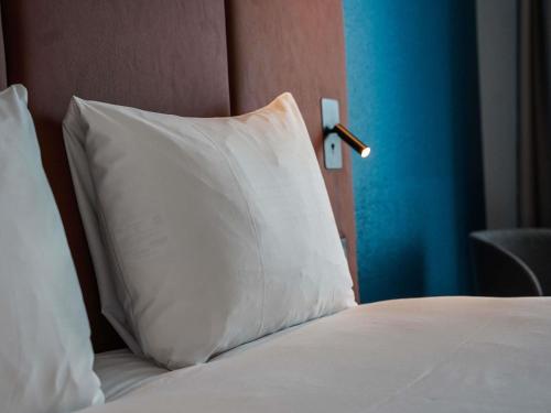 a white pillow sitting on top of a bed at ibis Bayeux Port En Bessin in Port-en-Bessin-Huppain