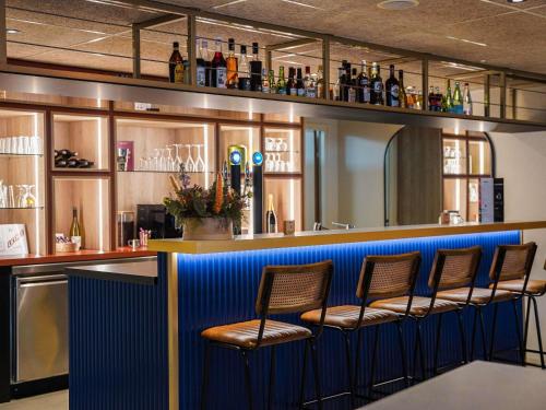 a bar with four chairs sitting at a bar at ibis Bayeux Port En Bessin in Port-en-Bessin-Huppain