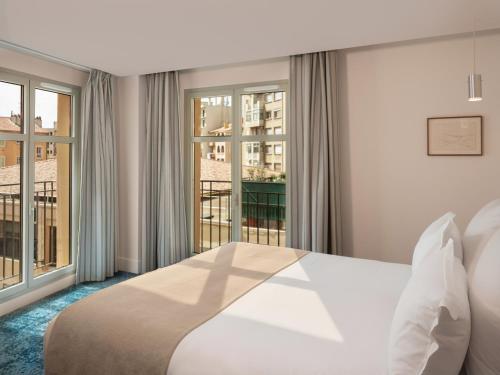 a hotel room with a bed and a large window at Hôtel Saint Christophe Aix en Provence Centre Ville in Aix-en-Provence