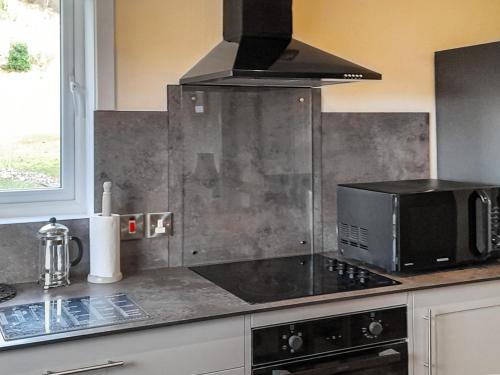 eine Küche mit Herd und Mikrowelle in der Unterkunft Sunnybank Cottage in Inveralligin