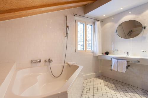a white bathroom with a tub and a sink at Chalet Annelis Apartments in Zermatt