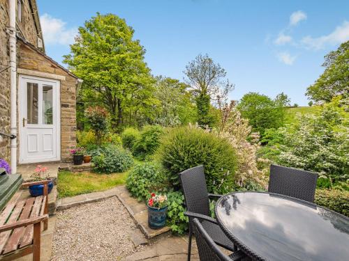 a patio with a table and chairs in a garden at Holme House Cottage in Oakworth