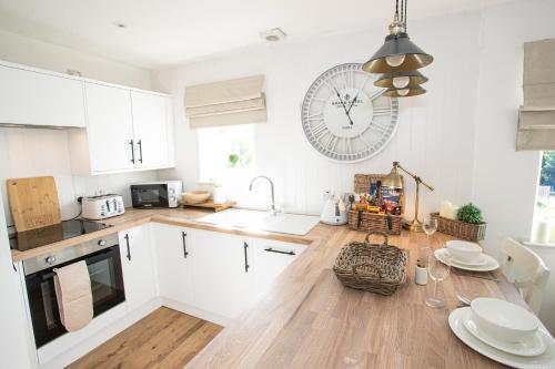 インバネスにあるLillymont Apartment - Inverness City Centreの白いキャビネットと壁掛け時計付きのキッチン