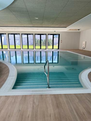 a large swimming pool in a building with windows at PINEA Resort in Pobierowo