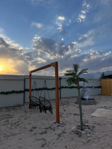 a swing and a palm tree on the beach at Issyk-Kul Glamping in Chon-Sary-Oy