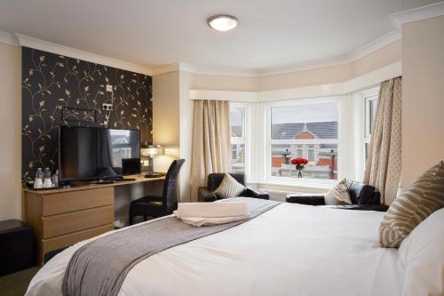 a bedroom with a bed and a tv and a window at Ashley Victoria in Blackpool