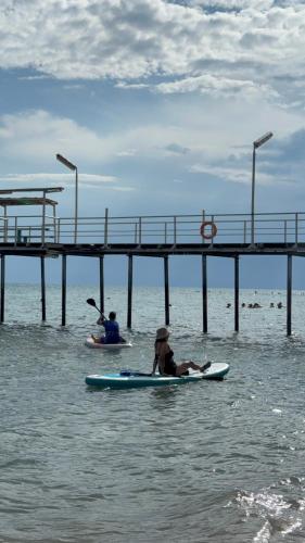 two people on surfboards in the water near a pier at Issyk-Kul Glamping in Chon-Sary-Oy