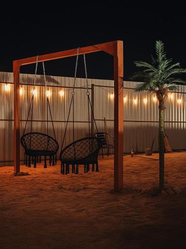 a group of swings and a palm tree at night at Issyk-Kul Glamping in Chon-Sary-Oy