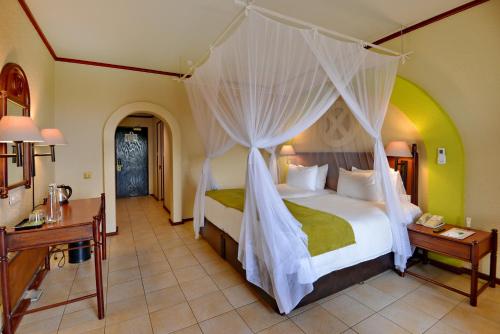 a bedroom with a bed with a canopy at Elephant Hills Resort in Victoria Falls