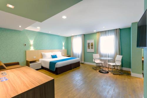 a hotel room with a bed and a table and chairs at Wyndham Sao Paulo Ibirapuera Convention Plaza in Sao Paulo