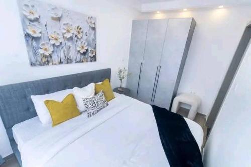 a bedroom with a white bed with yellow pillows at Wachabrabnbs in Nairobi