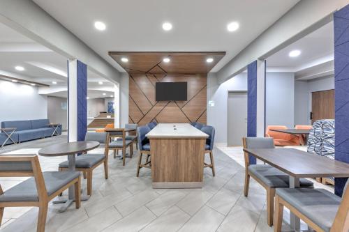 a waiting room with tables and chairs and a tv at Holiday Inn Express and Suites Granbury by IHG in Granbury