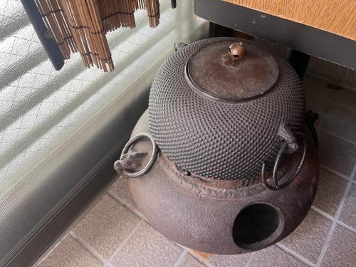 an old pot sitting on the floor next to a window at SUZUNONE The only private lodging in Tokyo 2 min walk natural hot springs near BIG super market ASAKUSA AKIHABARA SKYTREE nearby Japanese TATAMI style in Tokyo