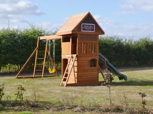 a small wooden playground with a slide and a swing at Railway Carriage Two - E5601 in Wetheringsett