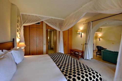 a bedroom with a large white bed with a canopy at Elephant Hills Resort in Victoria Falls