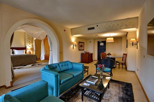 a living room with blue furniture and a bedroom at Elephant Hills Resort in Victoria Falls