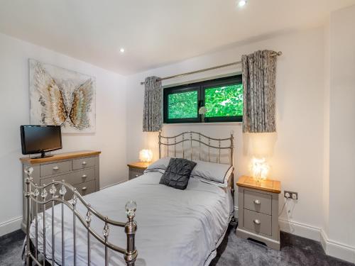 a bedroom with a bed and two dressers and two windows at Foxton Lodge - Uk47296 in Harrietsham
