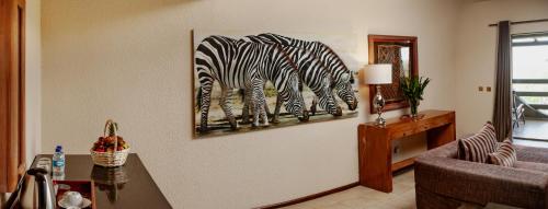 a living room with a painting of zebras on the wall at Elephant Hills Resort in Victoria Falls