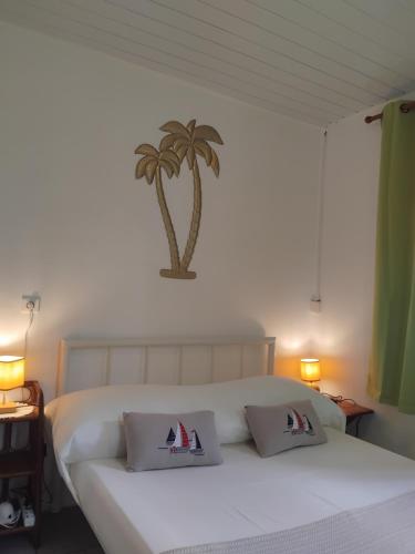 a bedroom with a white bed with a palm tree on the wall at La maison du Lac in Temae