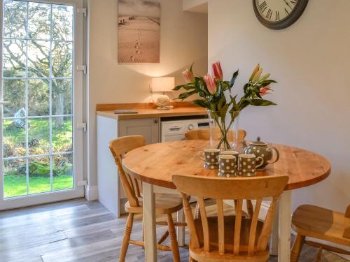 a kitchen with a wooden table and chairs and a clock at Clarksburn Blue in Monreith
