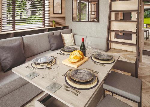 a dining room table with plates and a bottle of wine at Aber Bay Holiday Park in Aberystwyth