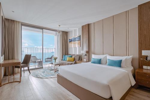a hotel room with a large bed and a balcony at Coastal Charm Panorama Bayview in Nha Trang