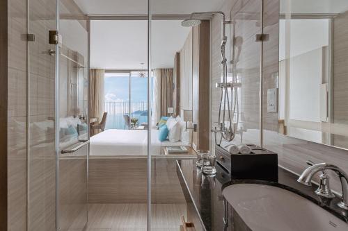 a bathroom with a shower and a sink and a bed at Coastal Charm Panorama Bayview in Nha Trang