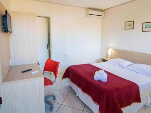 a hotel room with a bed and a red chair at Pousada Sol e Praaia in Torres