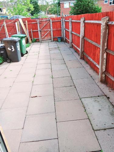 a sidewalk with a red fence and a trash can at EEE Homes Wolverhampton in Wolverhampton