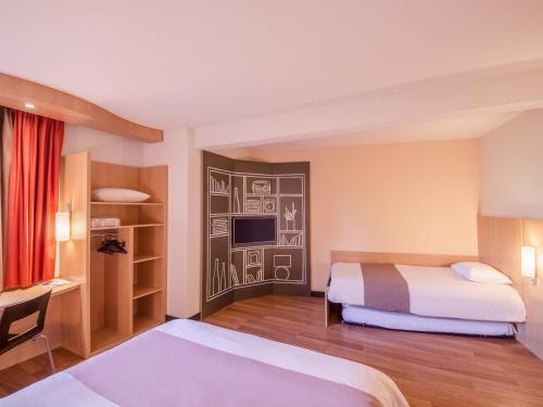 a hotel room with two beds and a desk at Ibis Sarlat Centre in Sarlat-la-Canéda
