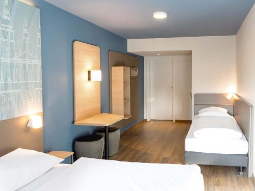 a room with two beds and a desk in it at B&B HOTEL Fulda-Hbf in Fulda