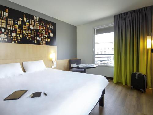 a hotel room with a large bed and a window at ibis Lyon Sud Vienne Saint-Louis in Vienne