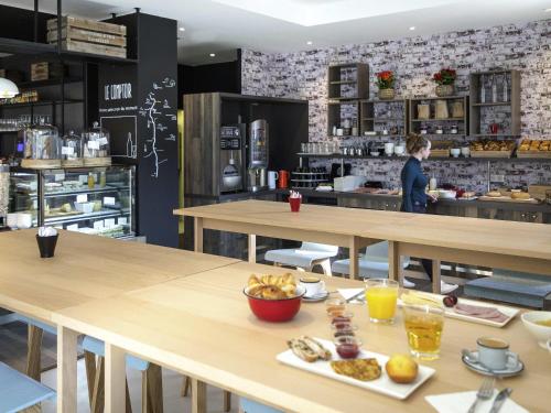 a restaurant with tables and a person in the kitchen at ibis Lyon Sud Vienne Saint-Louis in Vienne