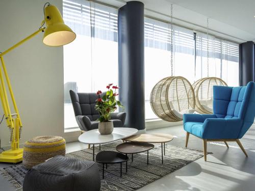 a living room with blue chairs and a table at ibis Lyon Sud Vienne Saint-Louis in Vienne