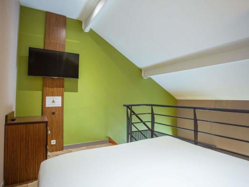 a bedroom with a bed and a flat screen tv at Hôtel Ibis Styles Bourges - Piscine extérieure chauffée - Restaurants à proximité in Bourges
